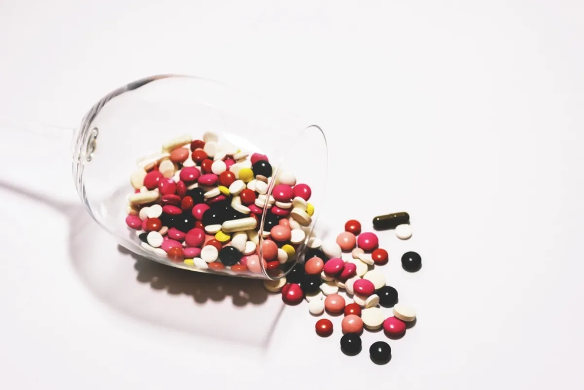 Medicine pills spilling from a glass, illustrating antimicrobial resistance cost