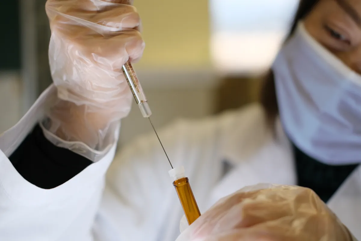 Scientist holding a syringe and vaccine vial, illustrating the Ebola vaccine trial