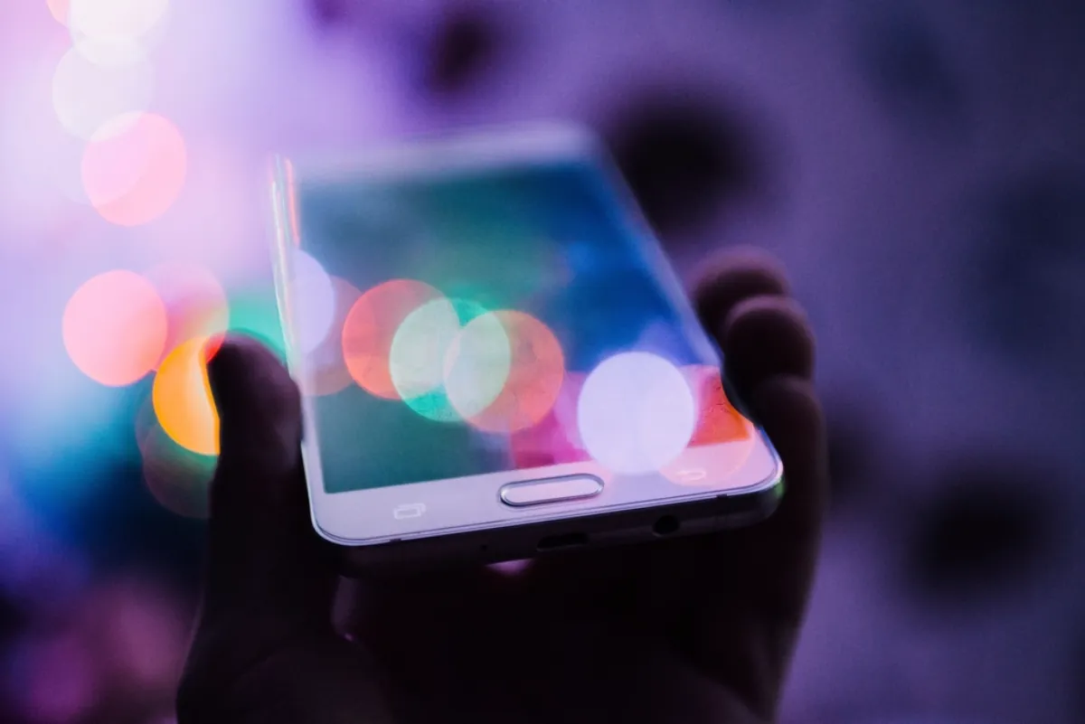 Smartphone held in hand with colourful lights, illustrating iPhone Duo screen crack reports